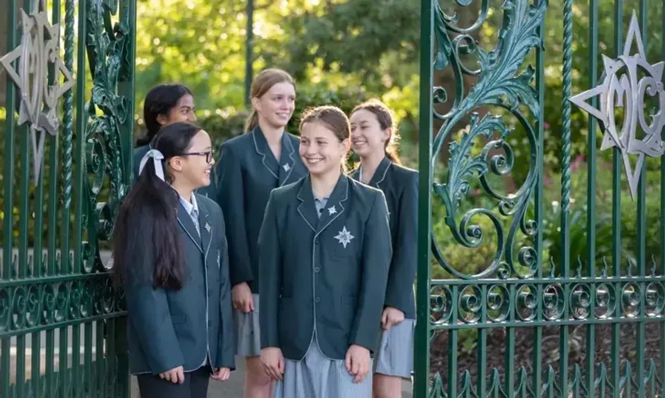 Un gruppo di studenti si trova davanti a un cancello in metallo decorato nel campus del Methodist Ladies' College.