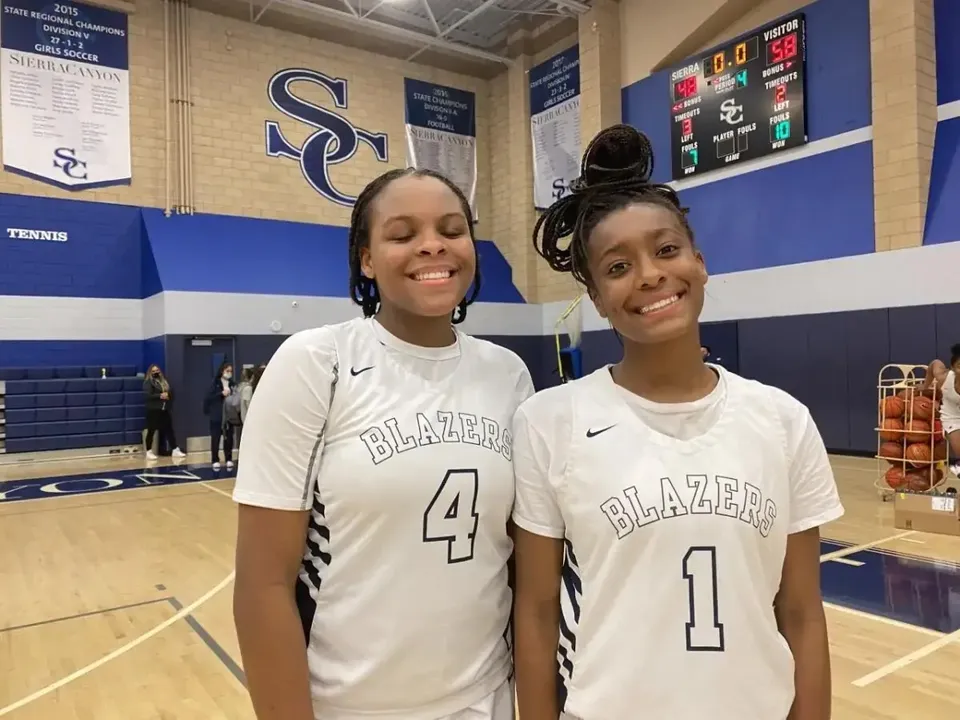 Due giocatrici di pallacanestro della Sierra Canyon School sorridono con maglie bianche nella palestra.