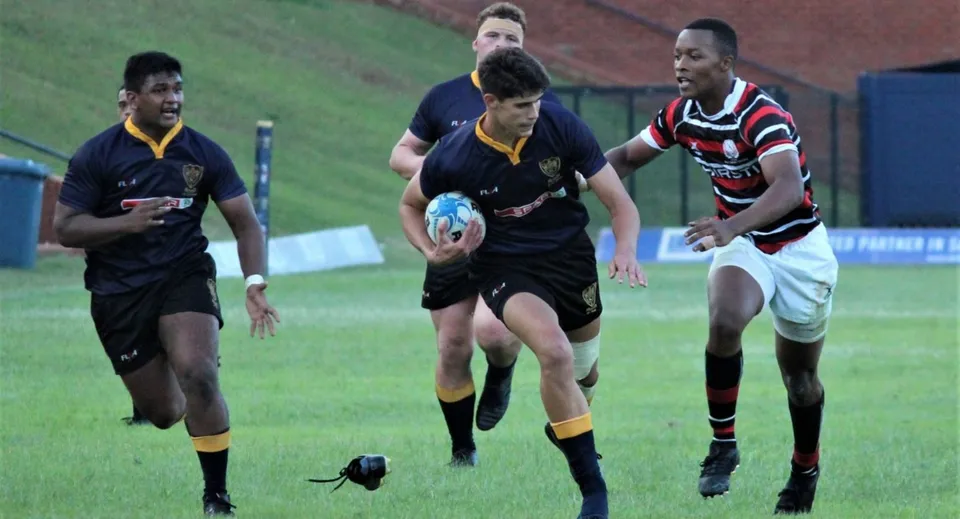 Un giocatore di rugby della Warminster School corre con la palla in campo durante una partita.