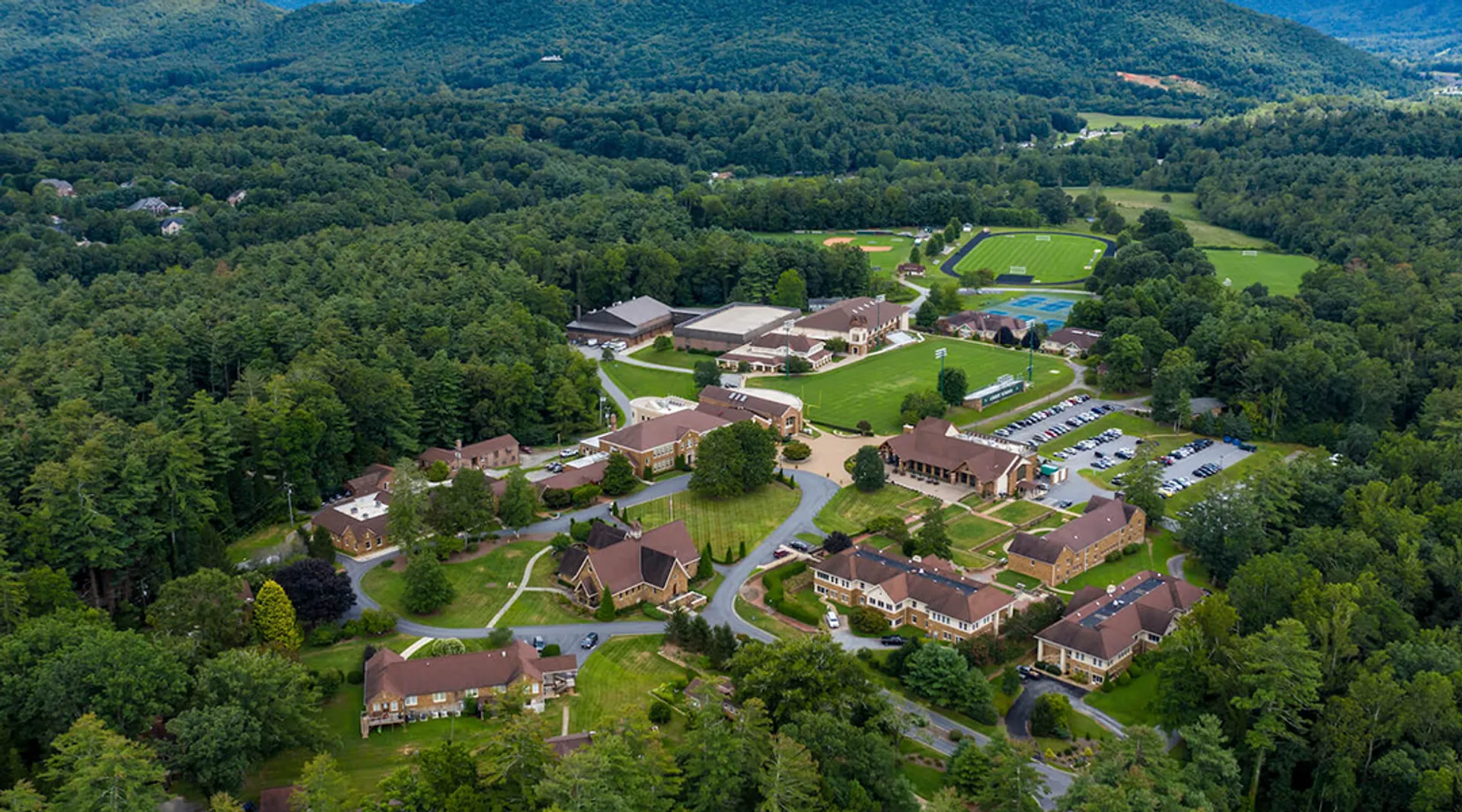 Un pittoresco paesaggio con boschi verdi e edifici nel campus della Christ School.
