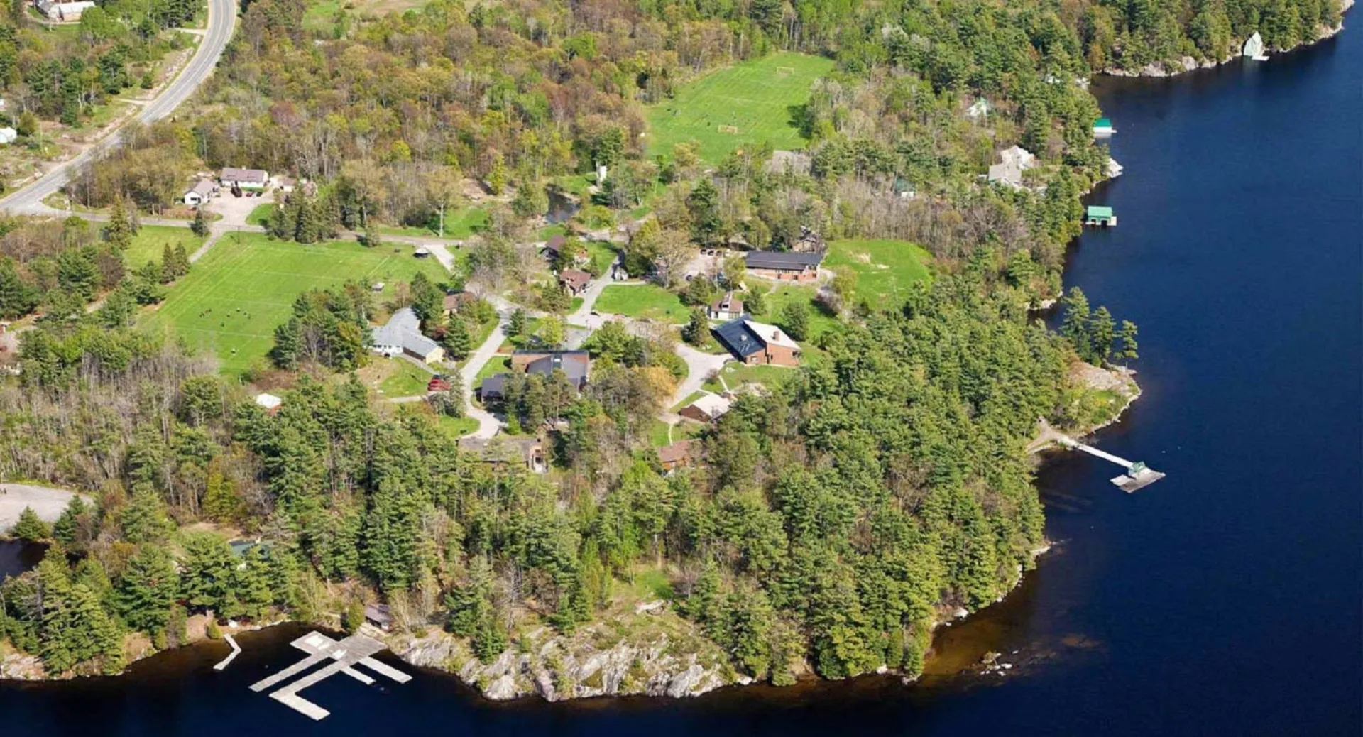 Un paesaggio boscoso con un sentiero tortuoso e un lago sullo sfondo vicino a Rosseau Lake College.