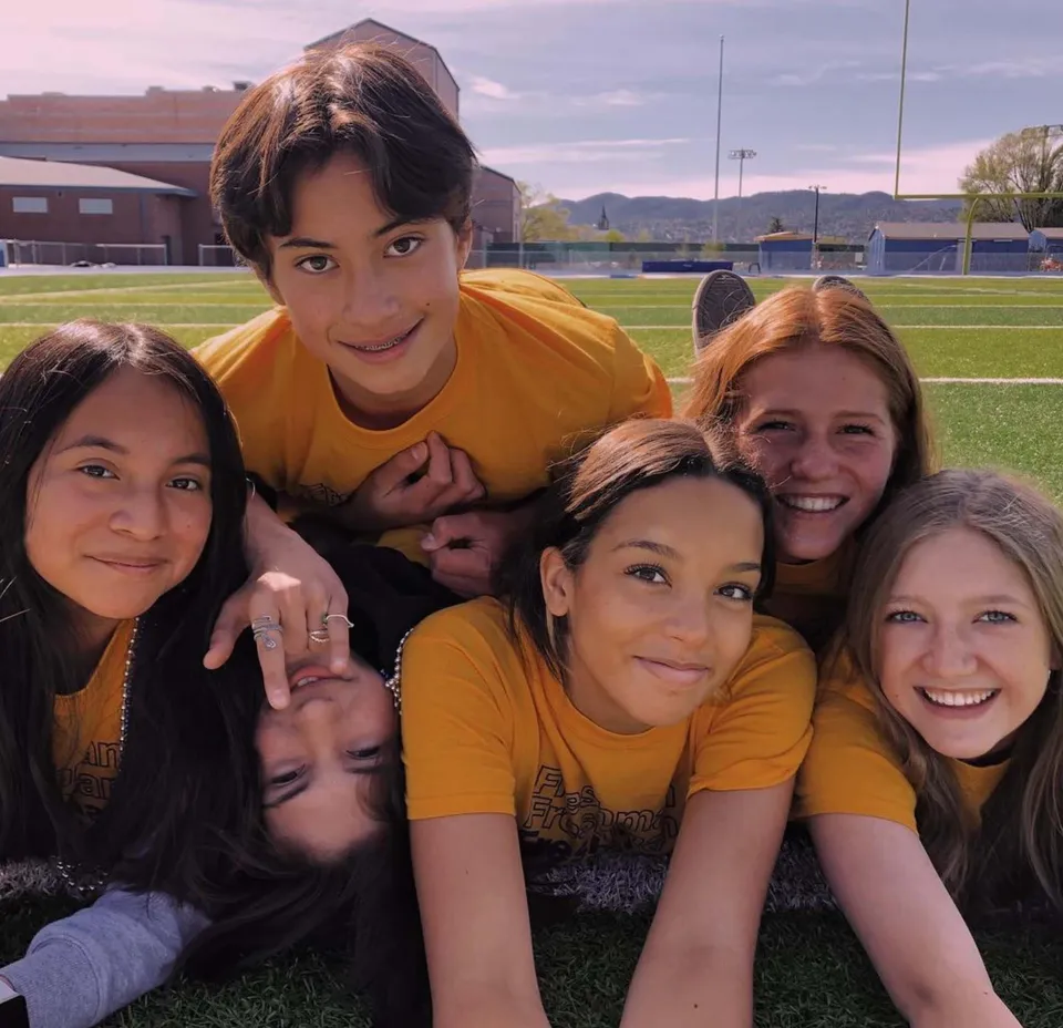 Un gruppo di studenti e studentesse della Prescott High School con maglietta gialla è insieme su un campo sportivo.