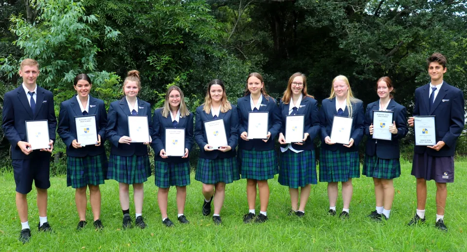 Un gruppo di studenti della Burnside State High School si trova all'aperto con dei certificati in mano.