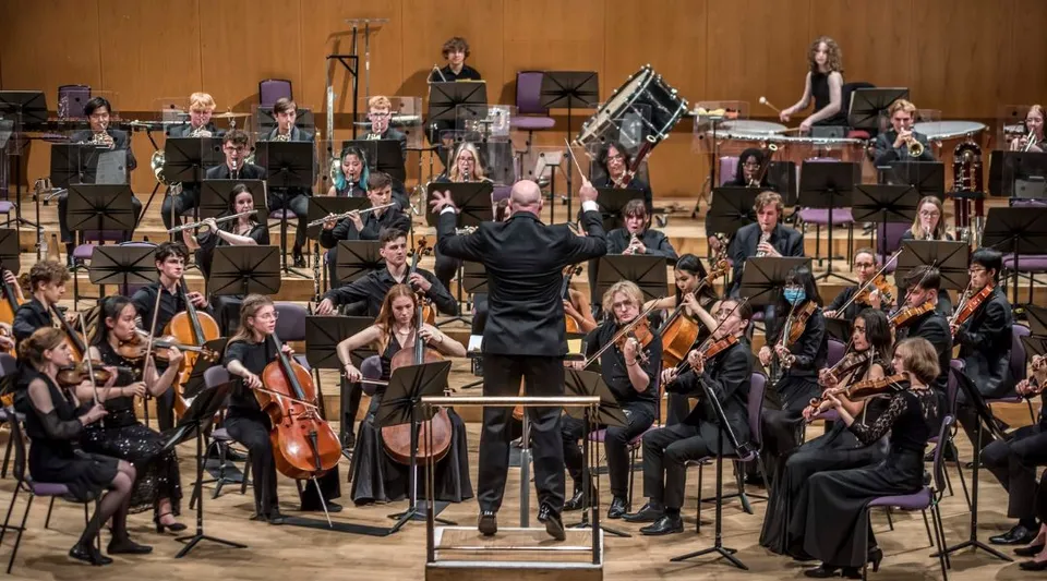 L'orchestra della Chetham’s School of Music esegue un concerto sul palco sotto la direzione del direttore d'orchestra.
