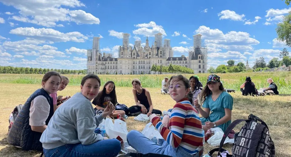 Un gruppo di studenti siede su un prato davanti al castello nel campus della Notre Dame Saint Joseph.