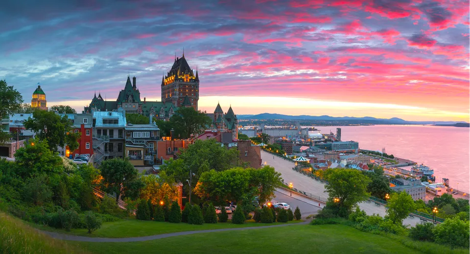 Vista panoramica del centro storico di Quebec con il Château Frontenac e il fiume durante un tramonto colorato.