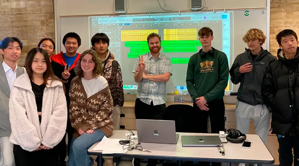 Studenti della San Domenico School lavorano insieme sui laptop in un'aula con un grande schermo.