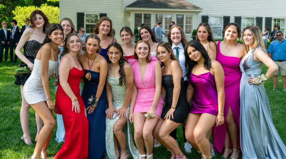 Un gruppo di giovani studentesse della Millbrook School posa in abiti formali davanti a una casa bianca all'aperto.