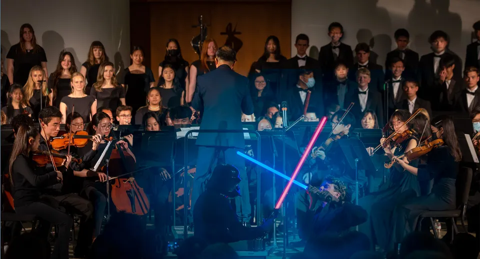 Un gruppo di studenti della Crean Lutheran High School si esibisce su un palco con illuminazione blu.