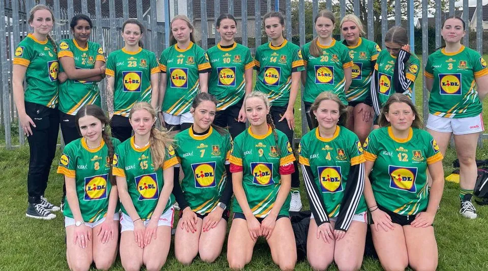 Un gruppo di giovani atlete in maglia verde e gialla posa sui campi sportivi del St. Patricks College a Cork.