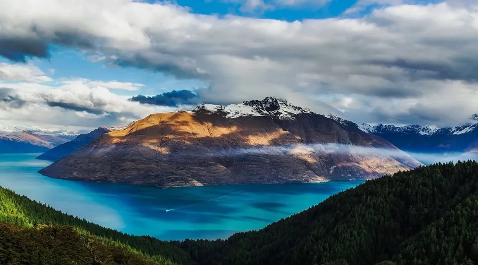 Una montagna si erge sopra un lago turchese con boschi verdi nei terreni del Coffs Harbour Senior College.