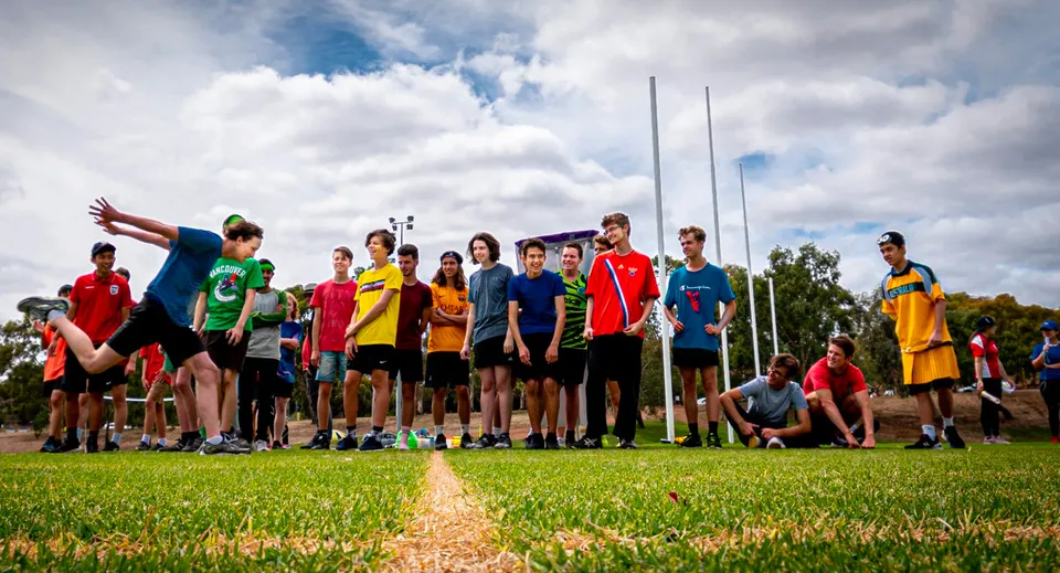 Un gruppo di giovani atleti si trova su un campo erboso nel campus della Australian Science and Mathematics School.