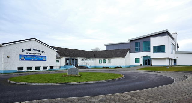 Das moderne mehrstöckige Gebäude von Scoil Mhuire (Strokestown) mit geschwungener Zufahrt und Grünfläche im Vordergrund.