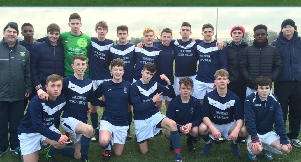 Un gruppo di giovani calciatori si trova sul campo sportivo della Mercy Secondary School.