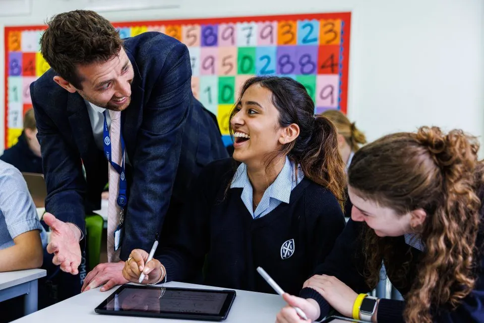 Gli studenti della Wycombe Abbey School discutono in classe con l'insegnante davanti a tabelloni didattici colorati.