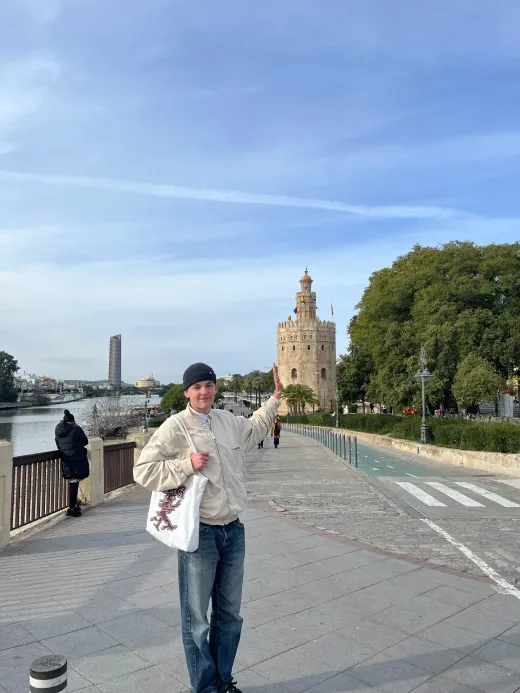 Ragazzo indica la Torre del Oro lungo il fiume a Siviglia