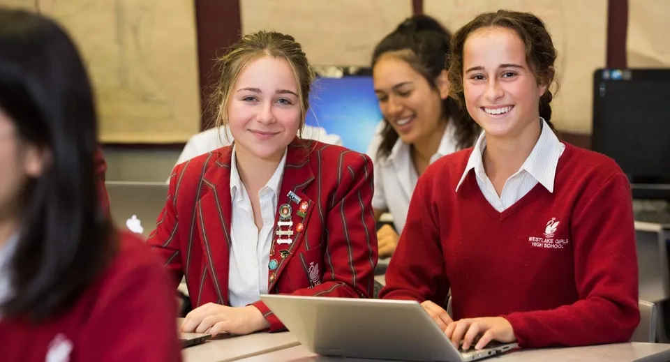 Due studentesse della Westlake Girls High School usano un laptop in un'aula con opere d'arte alle pareti.
