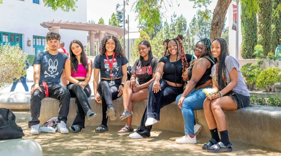Un gruppo di studenti è seduto insieme su una panchina all'aperto nel campus della San Diego State University.
