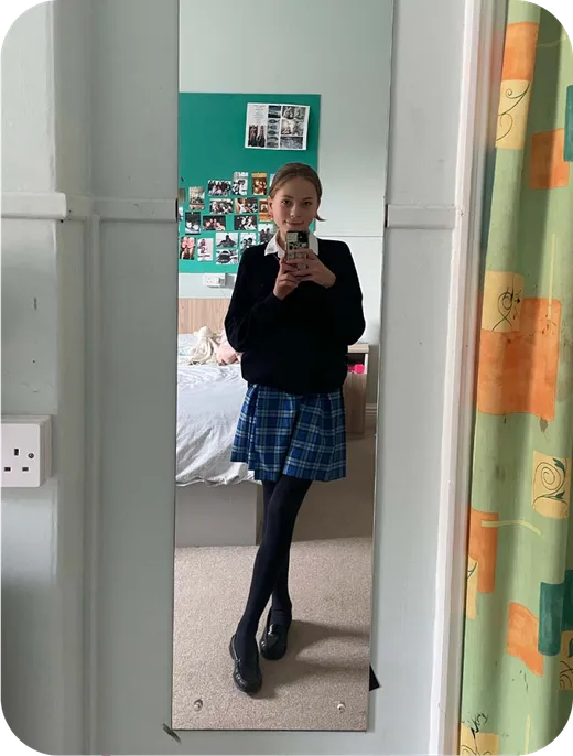 Estudiante con uniforme escolar se fotografía ante el espejo de su habitación