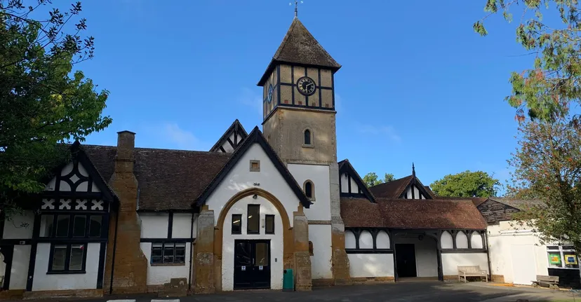 L'edificio in stile Tudor della Akeley Wood School si trova immerso nel verde sotto un cielo azzurro e limpido.