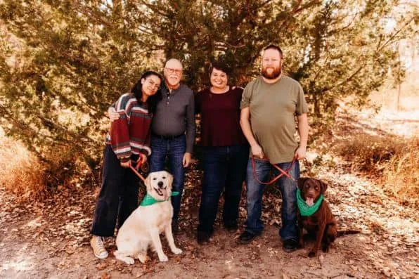 Inés posa con su familia anfitriona y sus dos perros en un camino entre árboles