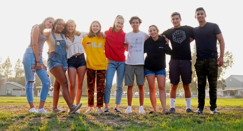 Un gruppo di studenti della Dunn School si trova insieme su un prato con case sullo sfondo.