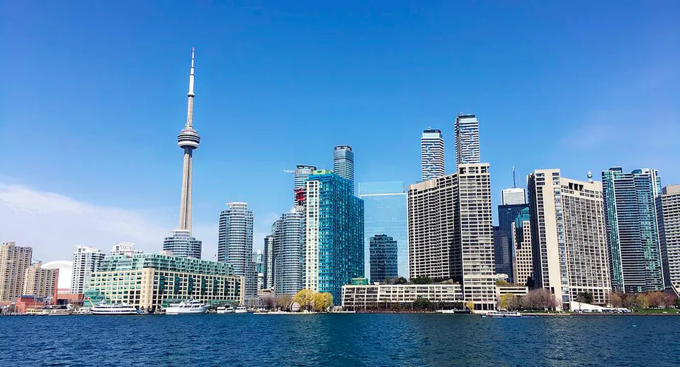 Uno skyline di moderni grattacieli con una torre caratteristica si riflette nell'acqua vicino al Bloor Collegiate Institute.