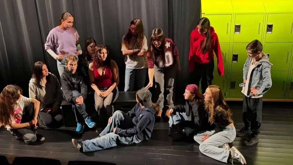 Un grupo de estudiantes de la École secondaire publique Rivière Rideau está en un escenario frente a casilleros de colores.