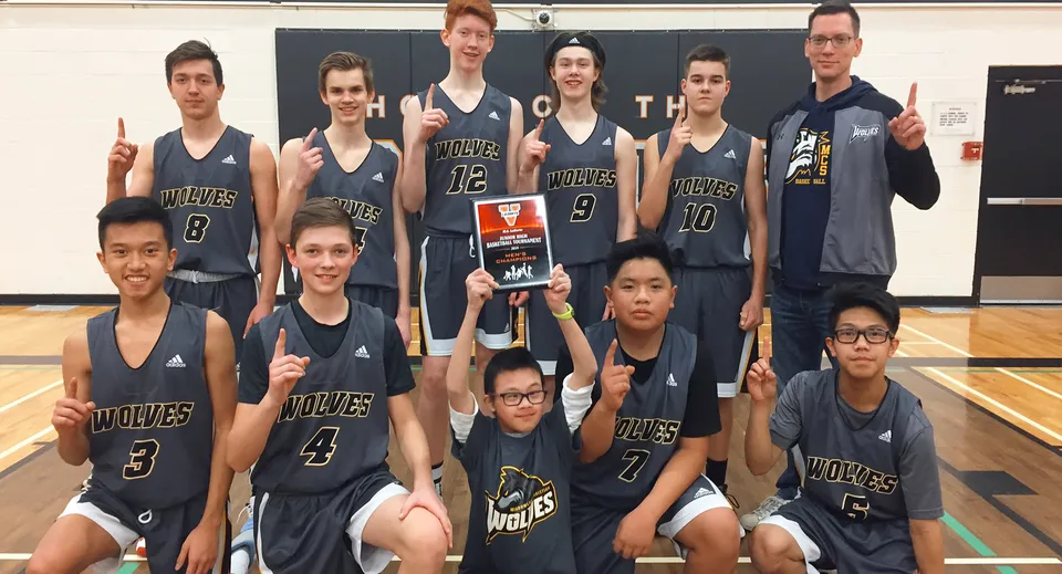 Un gruppo di studenti della M.E. LaZerte Composite High School posa insieme in palestra con le proprie maglie da basket.