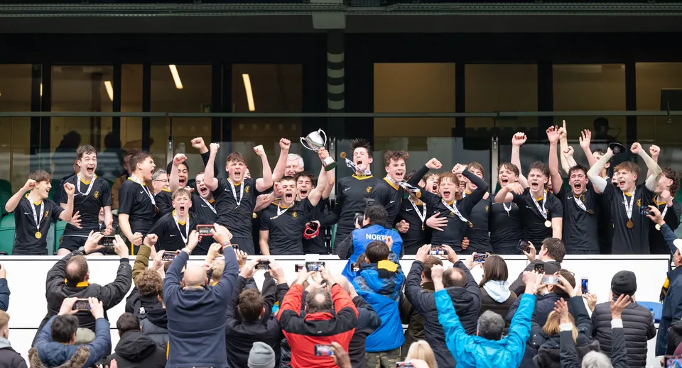 Un grande gruppo di studenti in divisa nera festeggia insieme nel campus del Wellington College.