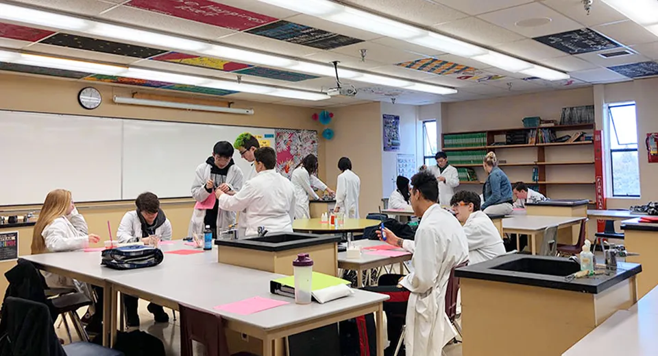 Studenti in camice da laboratorio lavorano in varie postazioni nell'aula della Aldergrove Community Secondary School.