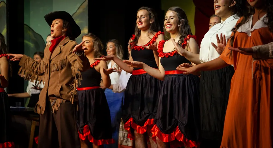 Un gruppo di studentesse del Dominican College Galway si esibisce su un palco in abiti tradizionali.