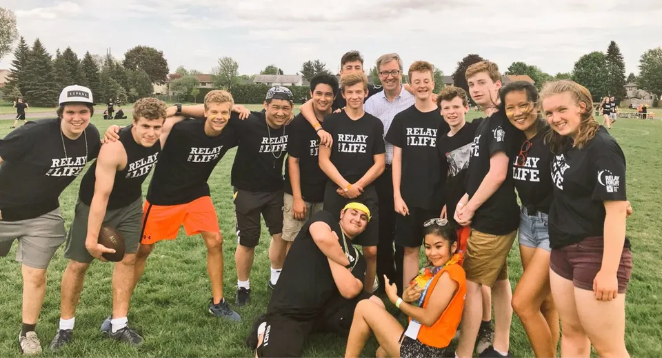 Un gruppo di studenti della Sir Robert Borden High School posa con magliette nere su un campo d'erba.