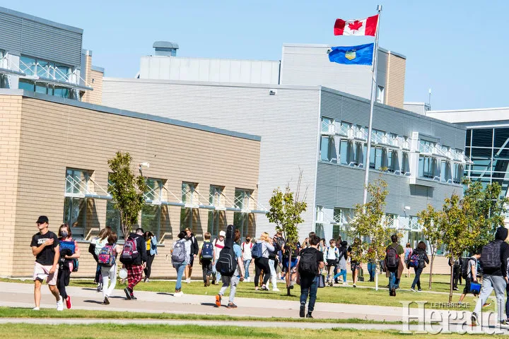 Un grupo de estudiantes camina sobre el césped frente al moderno edificio de Chinook High School.