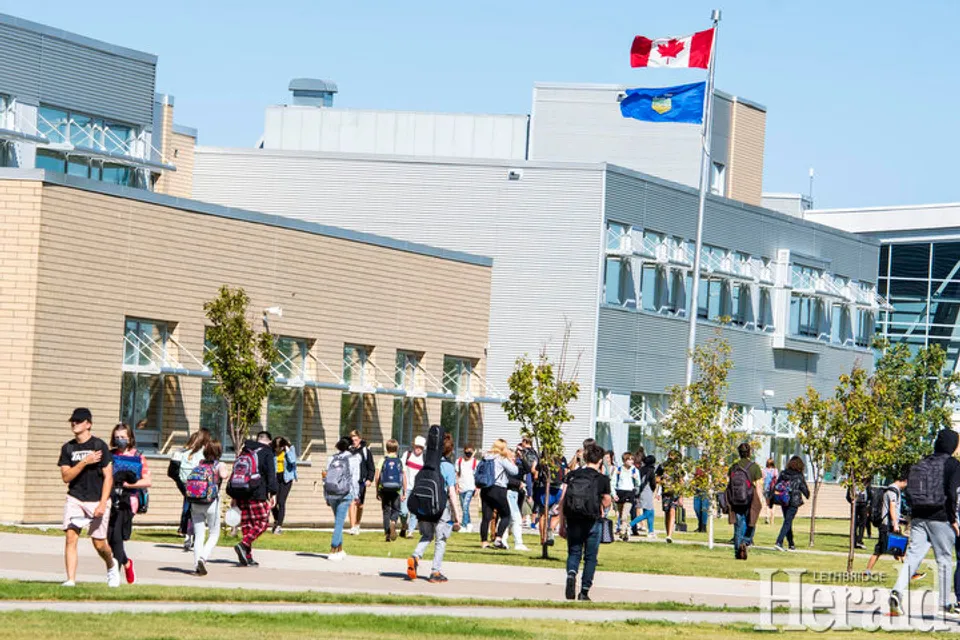 Un gruppo di studenti cammina su un prato davanti al moderno edificio della Chinook High School.