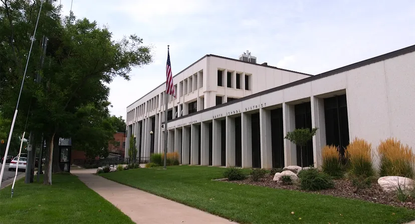 L'edificio moderno a più piani del Davis School District con pennone e aree verdi ben curate circondate da alberi.