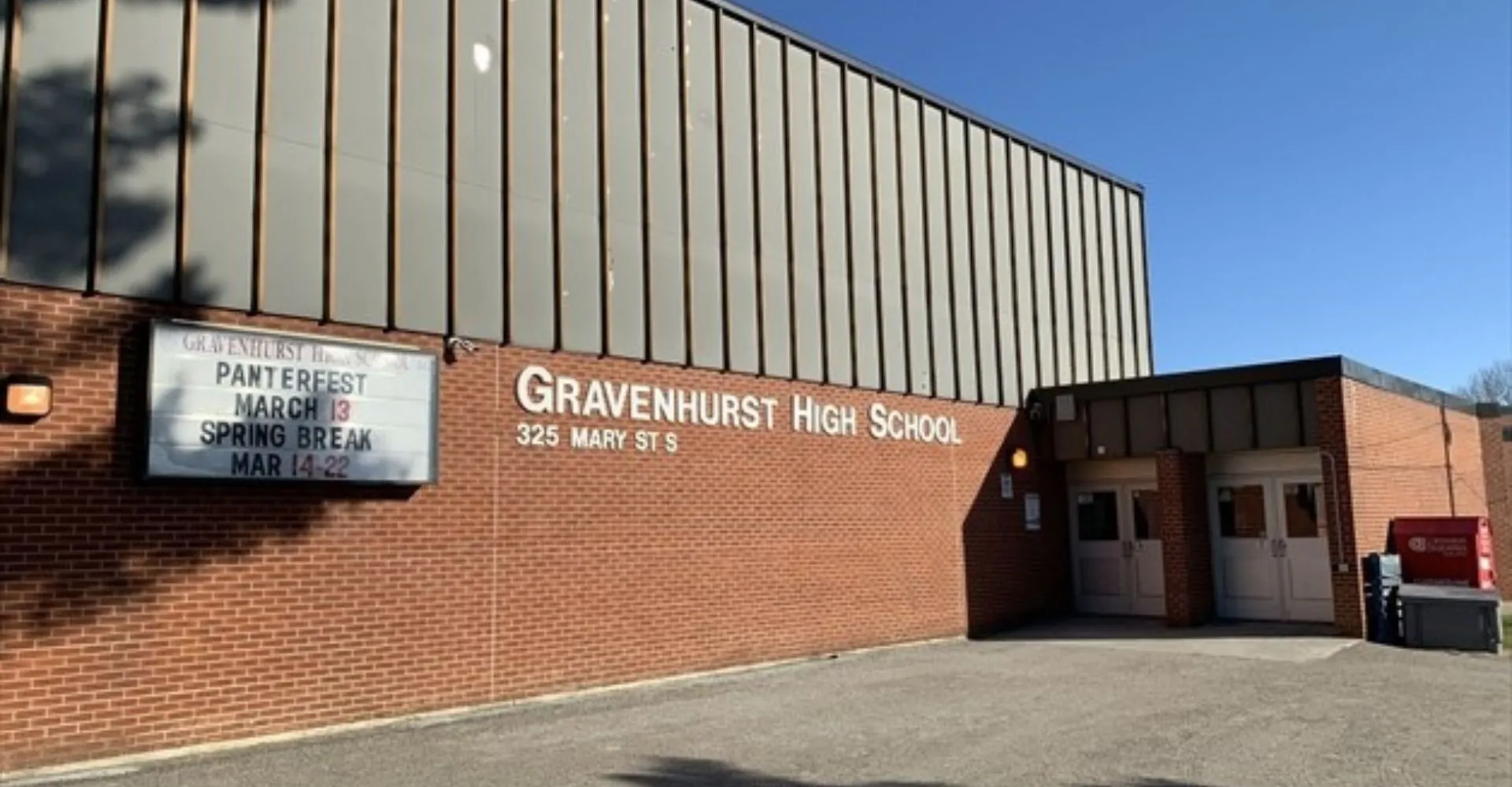 L'edificio in mattoni con l'insegna della Gravenhurst High School e il tabellone con le informazioni sugli eventi.