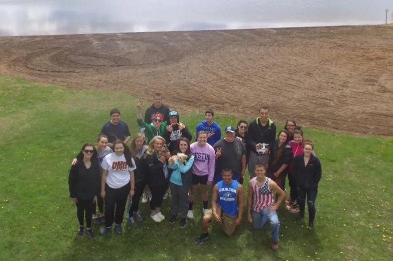 Grupo numeroso de estudiantes de intercambio posa sobre el césped junto a un lago