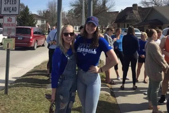 Dos chicas sonrientes vestidas de azul posan en una acera junto a la calle