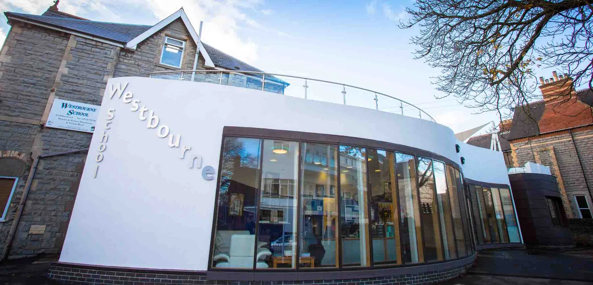 Una moderna estensione curva con grandi vetrate e la scritta Westbourne School.