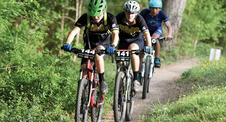 Tre ciclisti percorrono un sentiero nel bosco all'interno del terreno della Donahies Community School.