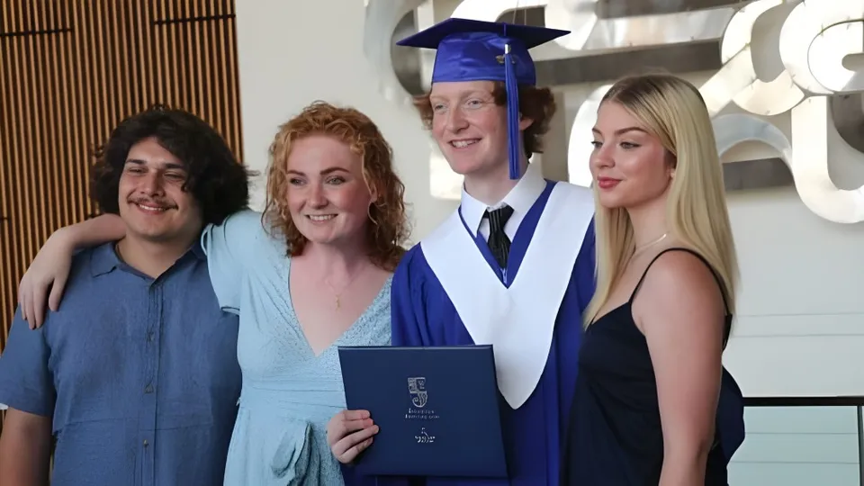 Quattro persone, tra cui un diplomato in toga, sono insieme a una cerimonia di diploma della Oak Park High School.