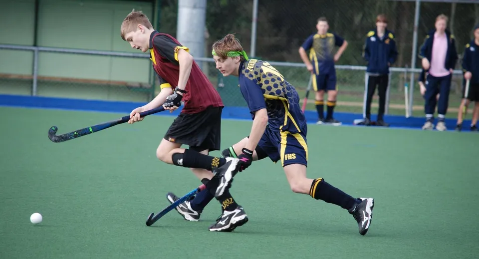 Due studenti della North Wicklow Educate Together Secondary School giocano una partita di hockey su prato sul campo sportivo.
