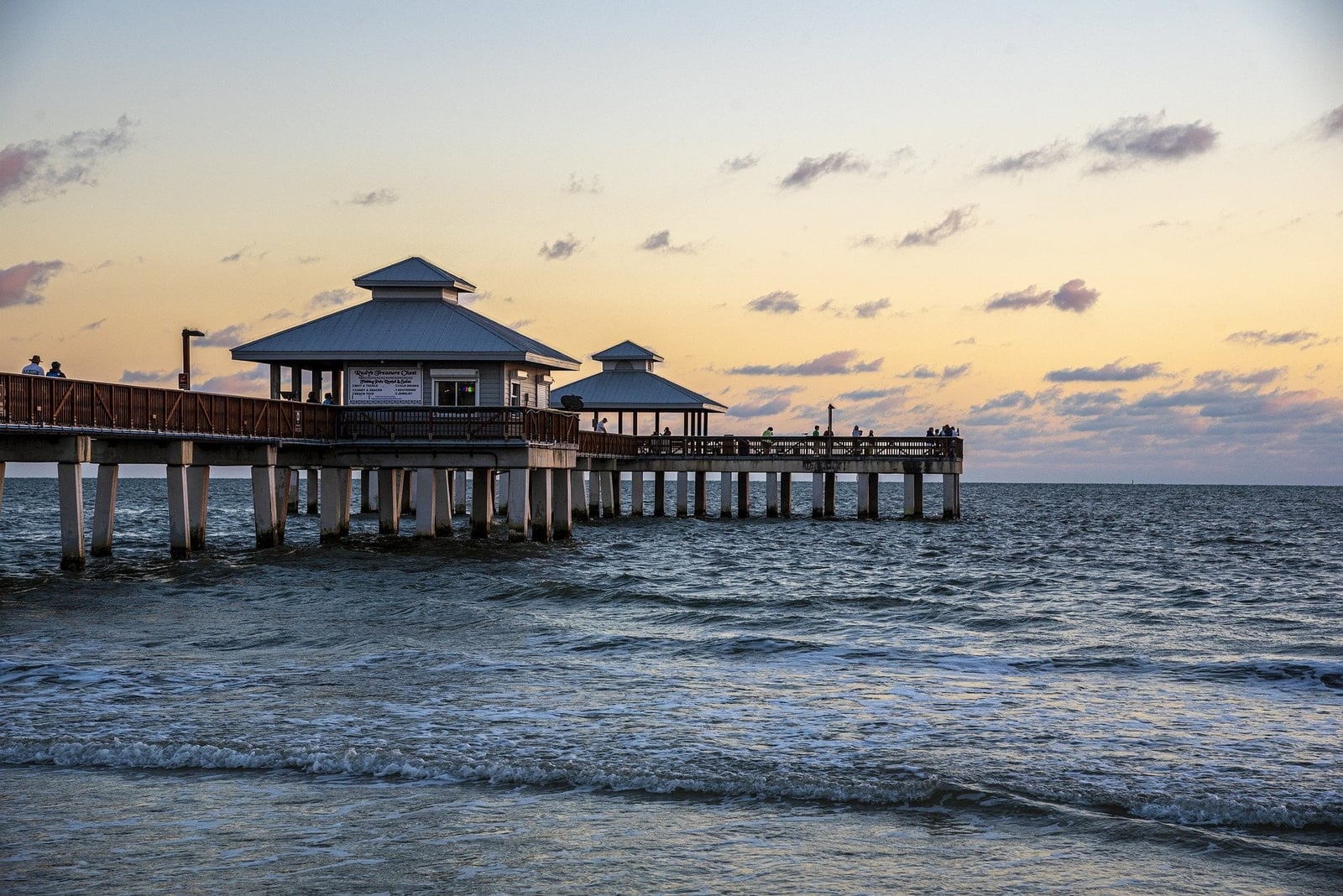 Seebrücke mit Pavillons ragt bei Sonnenuntergang ins Meer