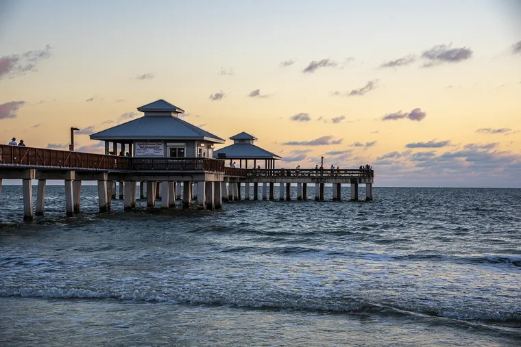 Seebrücke mit Pavillons ragt bei Sonnenuntergang ins Meer