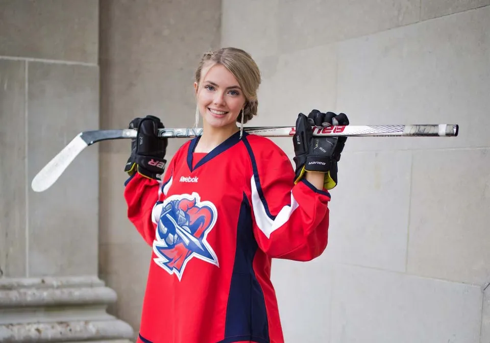 Una studentessa della Prince of Wales Collegiate si trova con una mazza da hockey davanti a una parete di cemento.