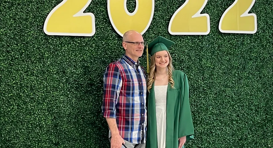Due diplomati della Martin Luther High School sono davanti a una siepe verde con l'anno 2022.