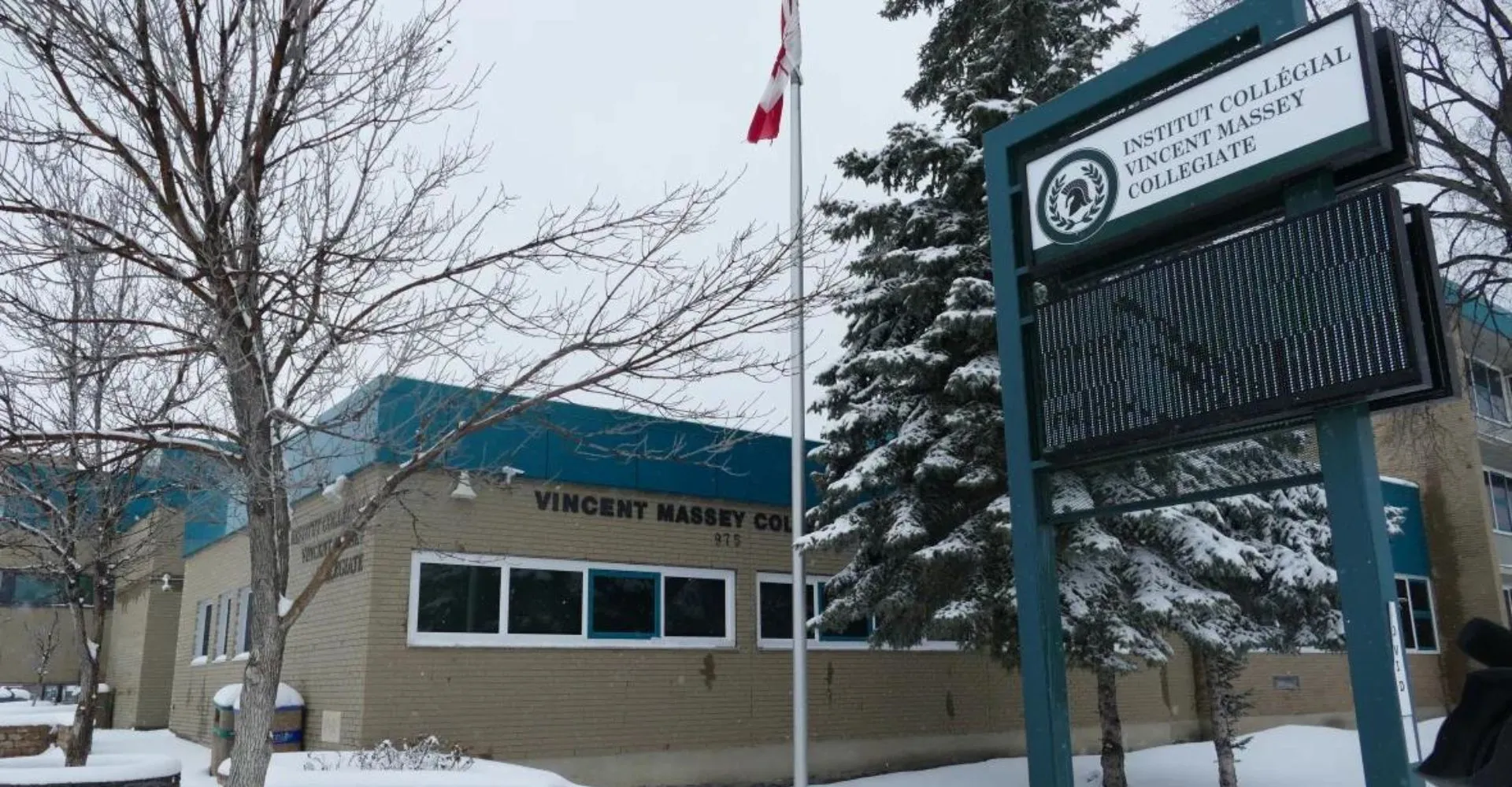 L'Institut Collégial Vincent Massey Collegiate mostra un edificio circondato da un paesaggio innevato con una bandiera canadese in primo piano.