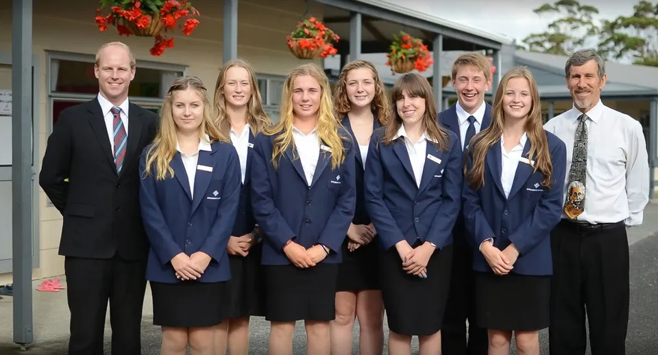 Un gruppo di studenti della Springbank School è insieme davanti a un edificio con decorazioni festive.