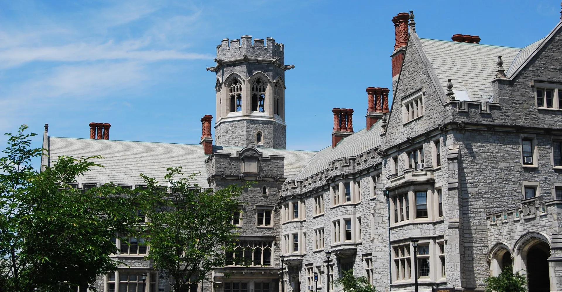 L'edificio in pietra della Emma Willard School con una torre e comignoli sotto un cielo azzurro.